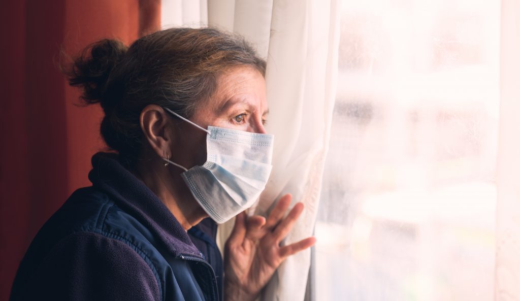 Woman in nursing home looks longingly out window during coronavirus lockdown